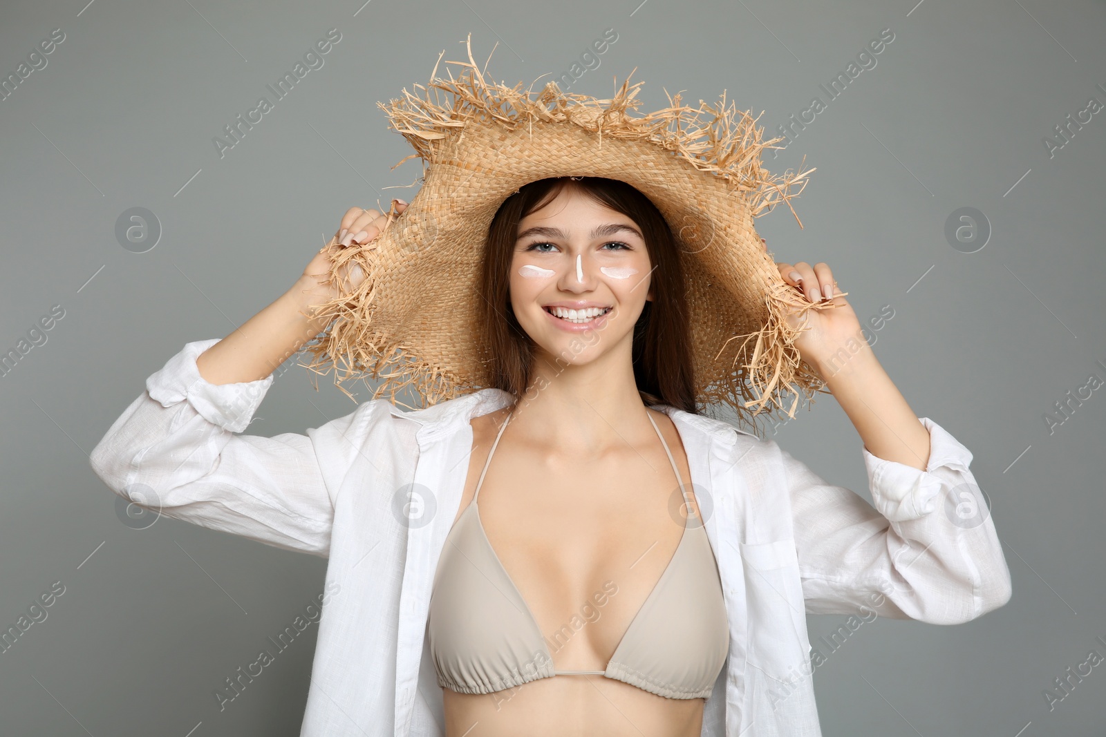Photo of Teenage girl with sun protection cream on her face against grey background