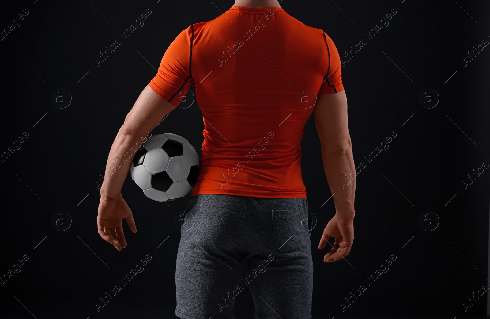 Photo of Athletic man with soccer ball on black background, closeup