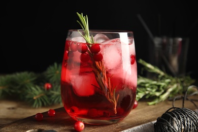 Photo of Tasty refreshing cranberry cocktail with rosemary on wooden table