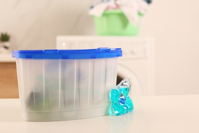 Laundry container and washing detergent capsule on table indoors