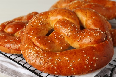 Photo of Tasty freshly baked pretzels on cooling grid, closeup view