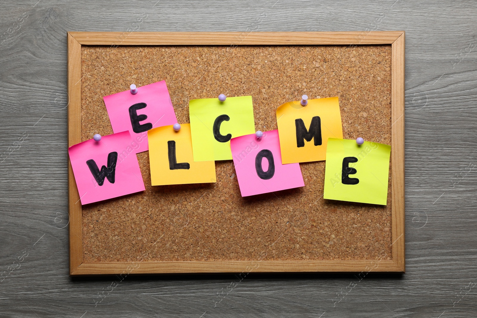 Photo of Corkboard with word Welcome on wooden table, top view