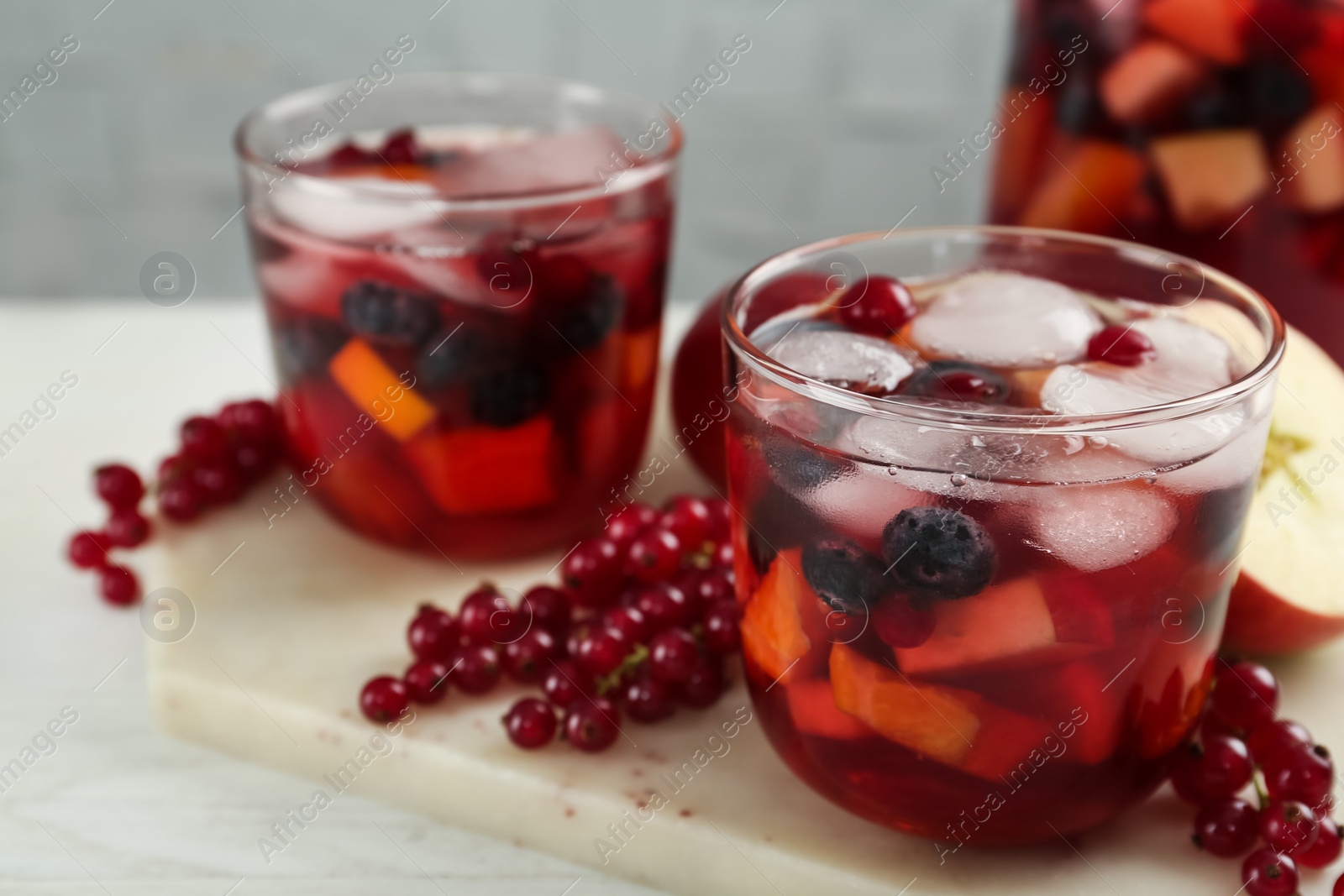 Photo of Delicious Red Sangria and ingredients on white wooden table, closeup. Space for text