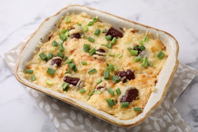 Photo of Tasty sausage casserole in baking dish on white marble table, closeup