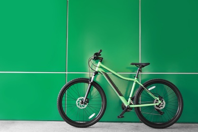 Photo of New modern color bicycle near green wall outdoors