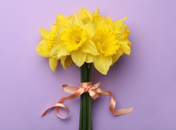 Beautiful daffodil bouquet on violet background, top view