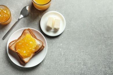 Flat lay composition with toast bread, jam and butter on grey background