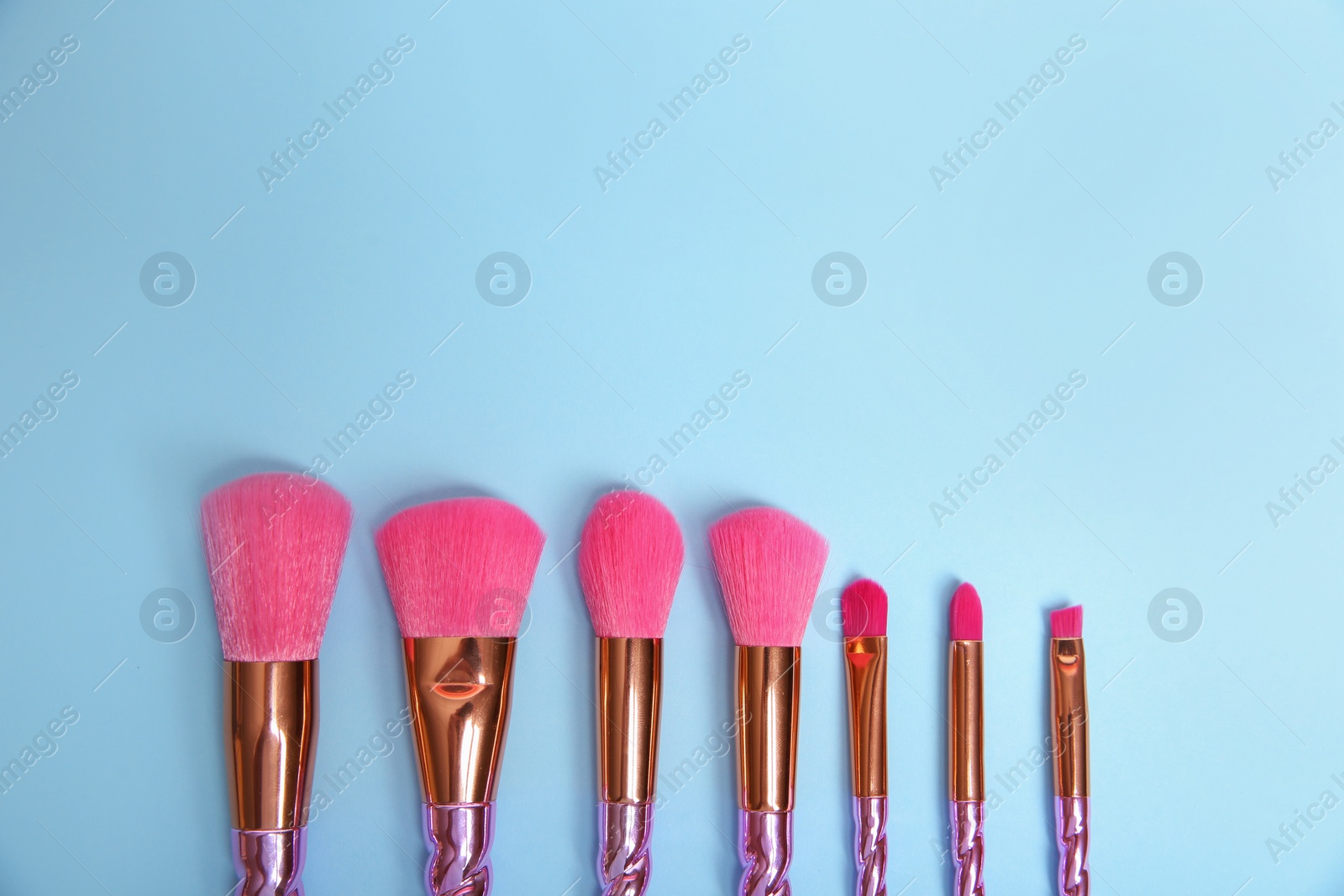 Photo of Flat lay composition with set of professional makeup brushes on light blue background. Space for text