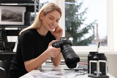 Photo of Professional photographer with digital camera at table in office