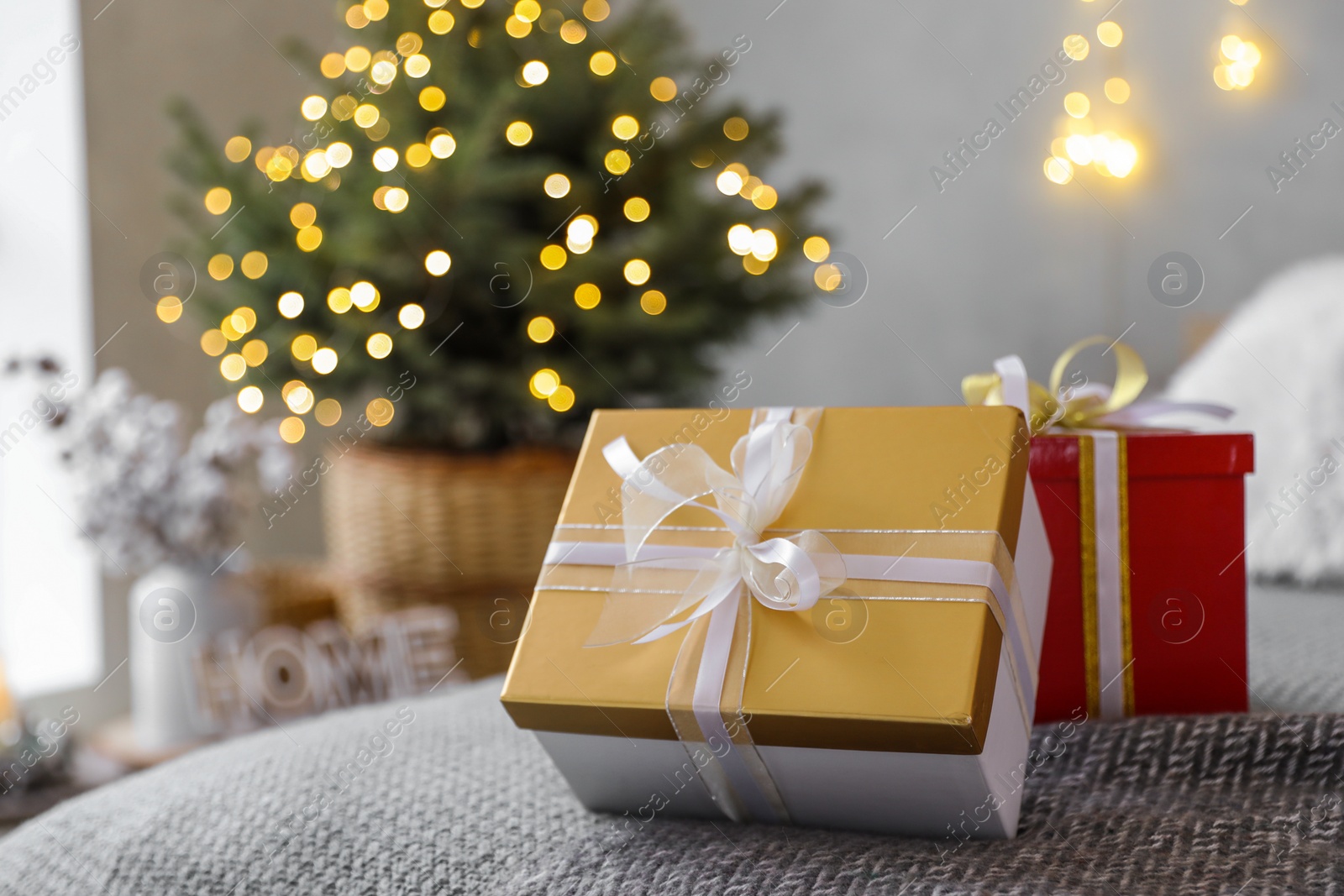 Photo of Christmas gift boxes on bed in festive interior