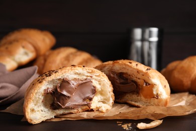 Fresh croissants with chocolate on wooden table, closeup. Space for text