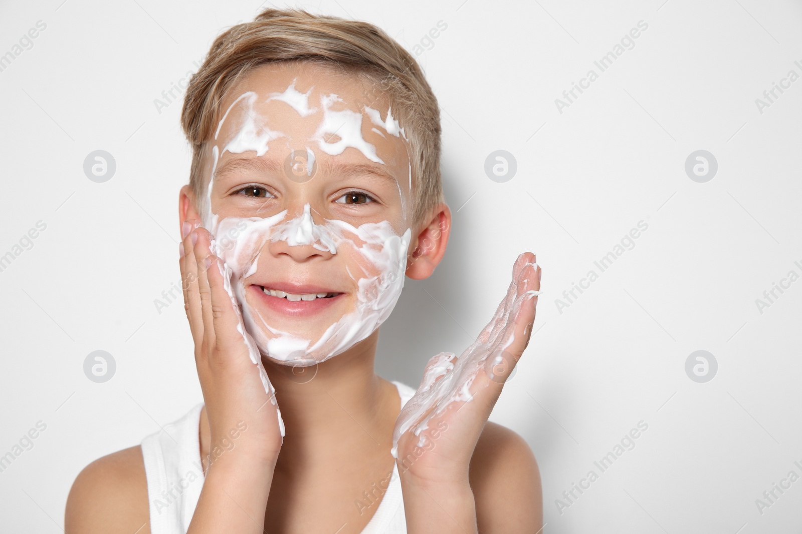 Photo of Cute little boy with soap foam on face against white background