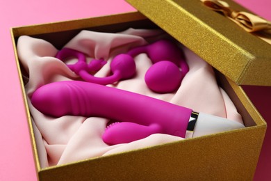 Photo of Sex toys in gift box on pink background, closeup