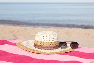 Photo of Beach towel with straw hat and sunglasses on sand near sea