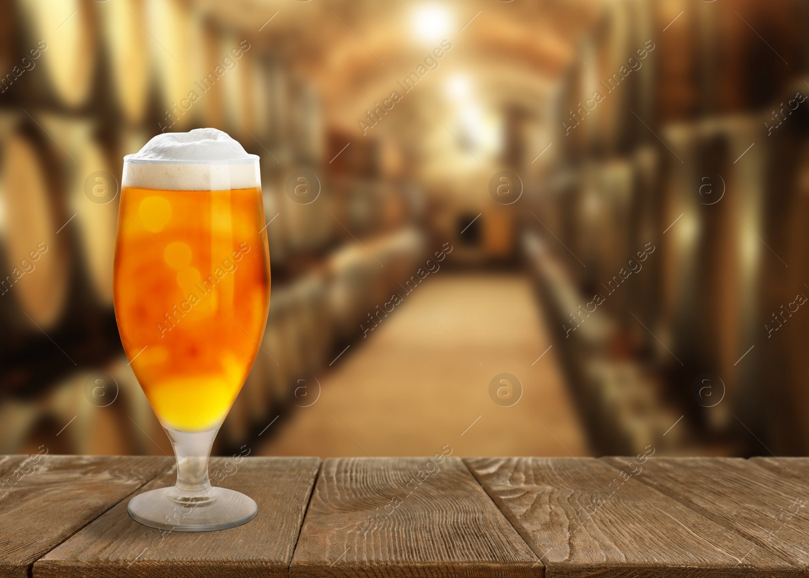 Image of Glass of tasty beer on wooden table in cellar with large barrels, space for text