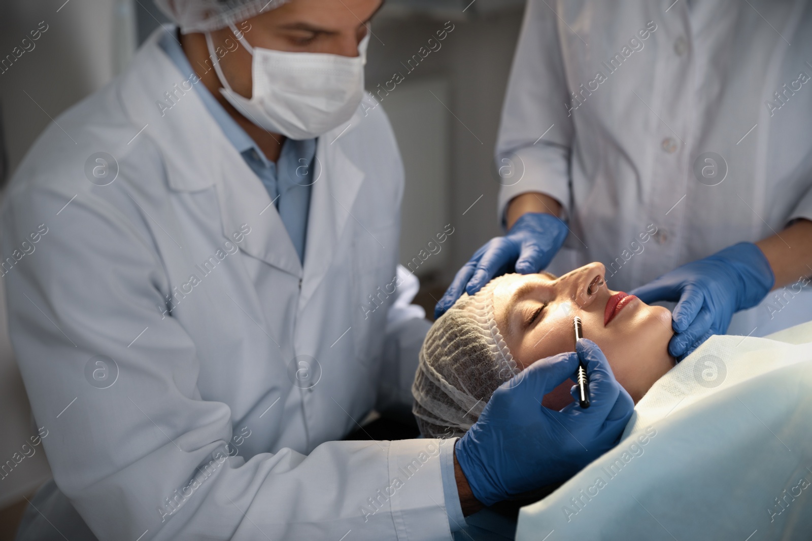 Photo of Doctor and nurse preparing female patient for cosmetic surgery in clinic