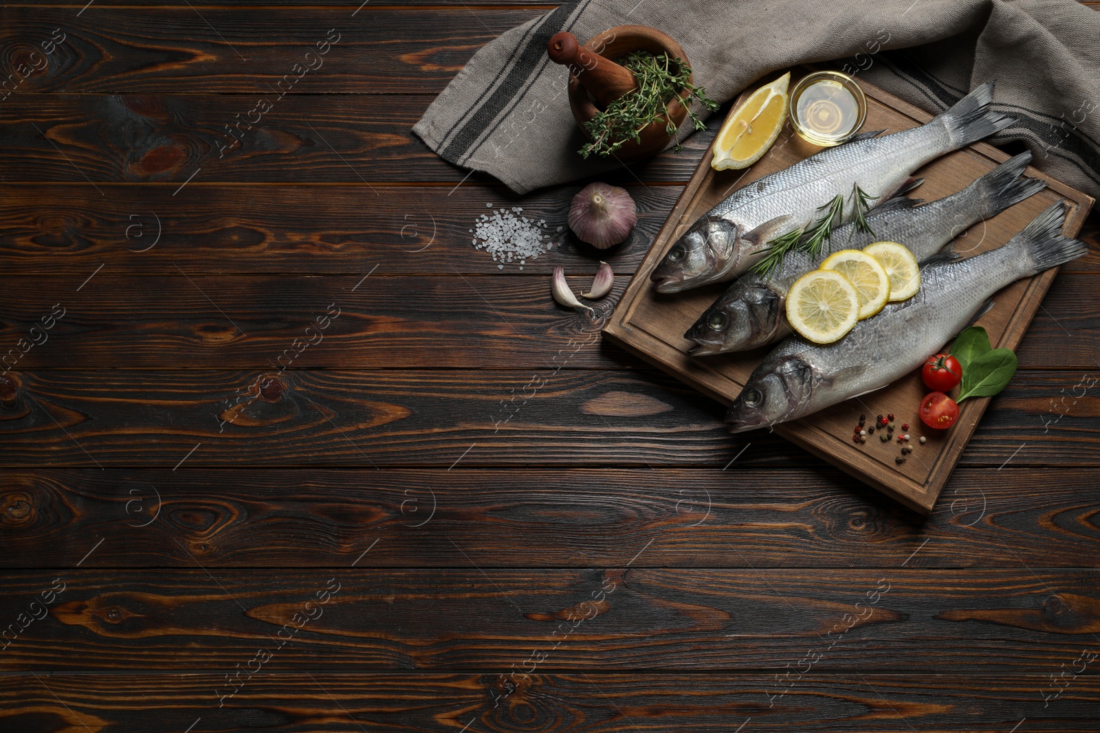 Photo of Sea bass fish and ingredients on wooden table, flat lay. Space for text