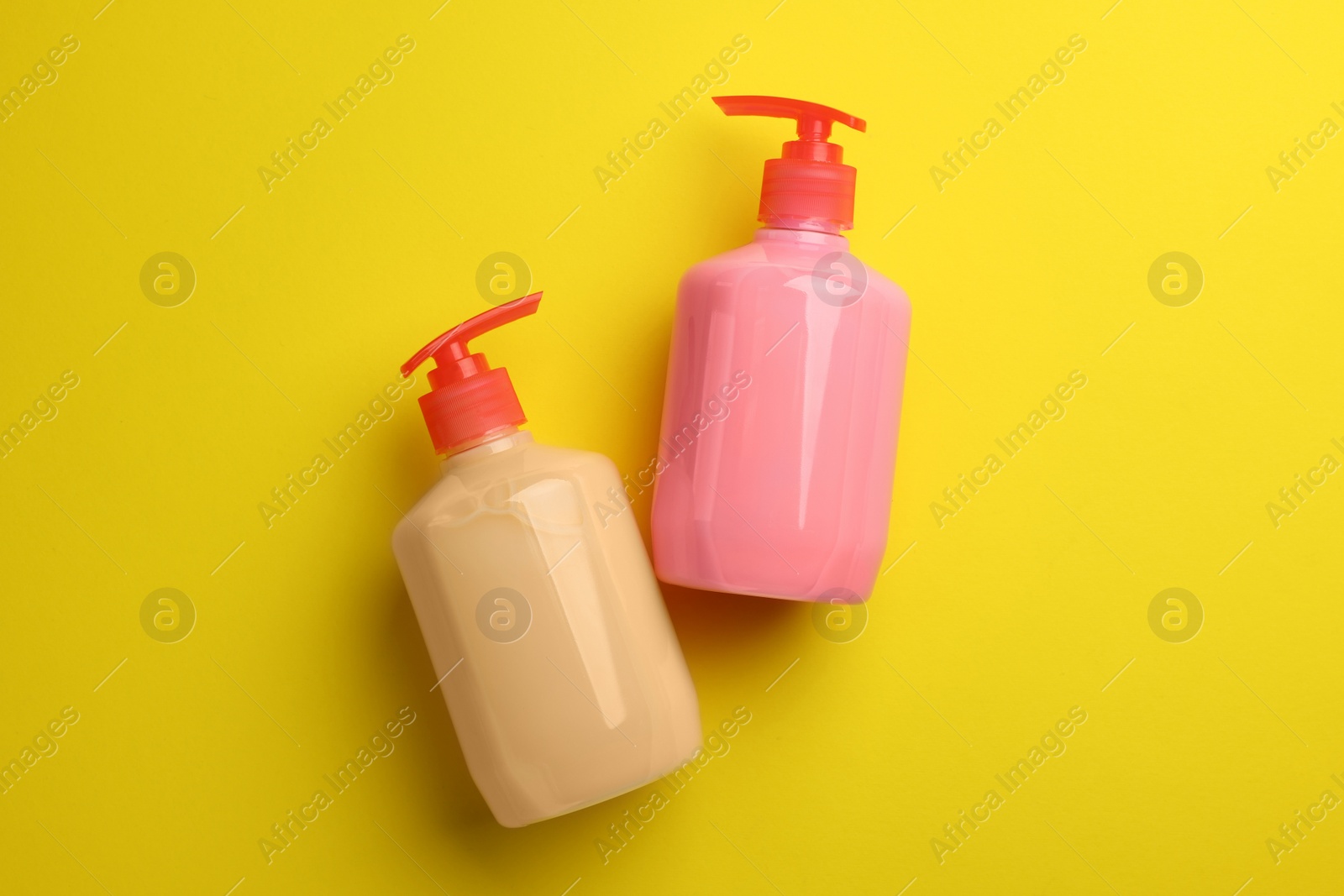 Photo of Bottles of liquid soap on yellow background, flat lay