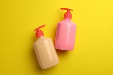Photo of Bottles of liquid soap on yellow background, flat lay