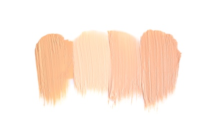 Samples of different foundation shades on white background, top view