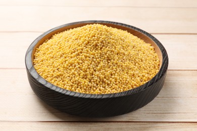 Photo of Millet groats in bowl on light wooden table
