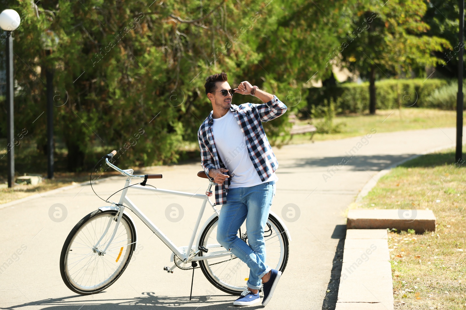 Photo of Handsome young hipster man with bicycle in park