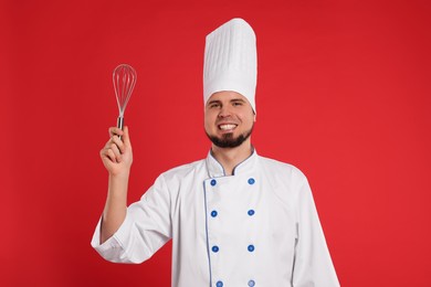 Happy professional confectioner in uniform holding whisk on red background