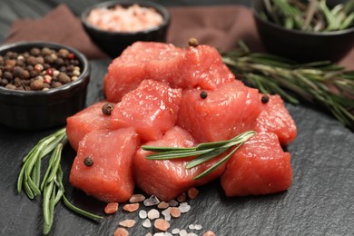 Cooking delicious goulash. Raw beef meat with rosemary and spices on slate board, closeup