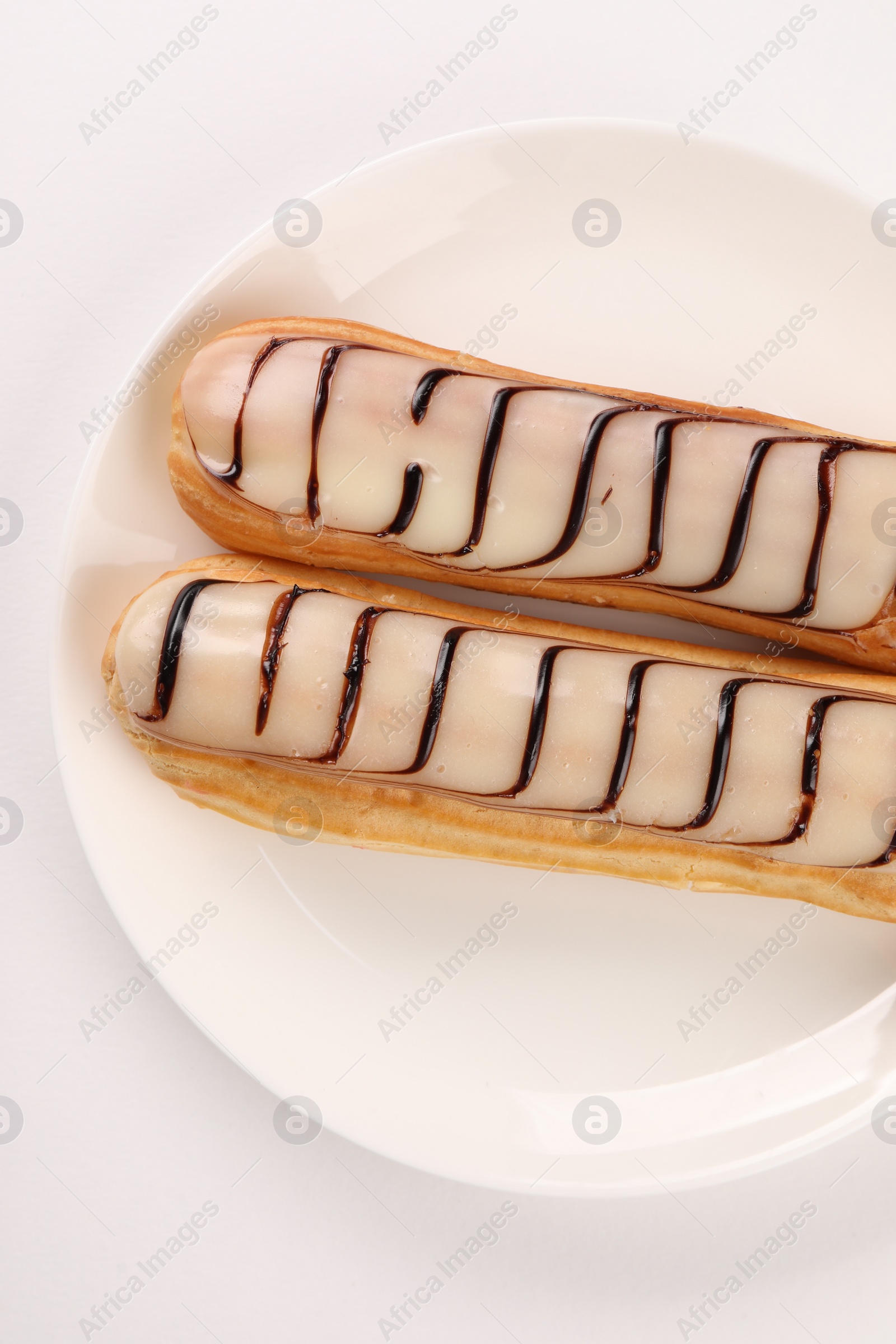 Photo of Delicious eclairs covered with glaze on white background, top view