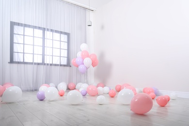 Room decorated with colorful balloons near wall