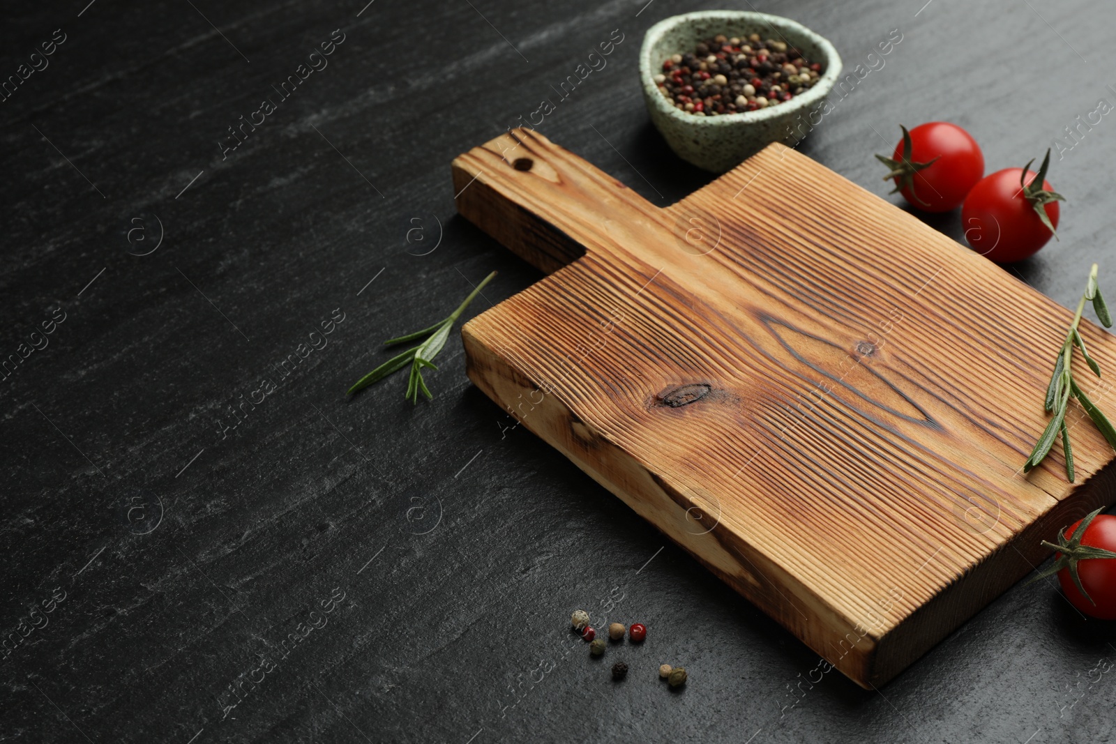 Photo of Wooden cutting board, fresh tomatoes and different spices on grey textured table. Space for text