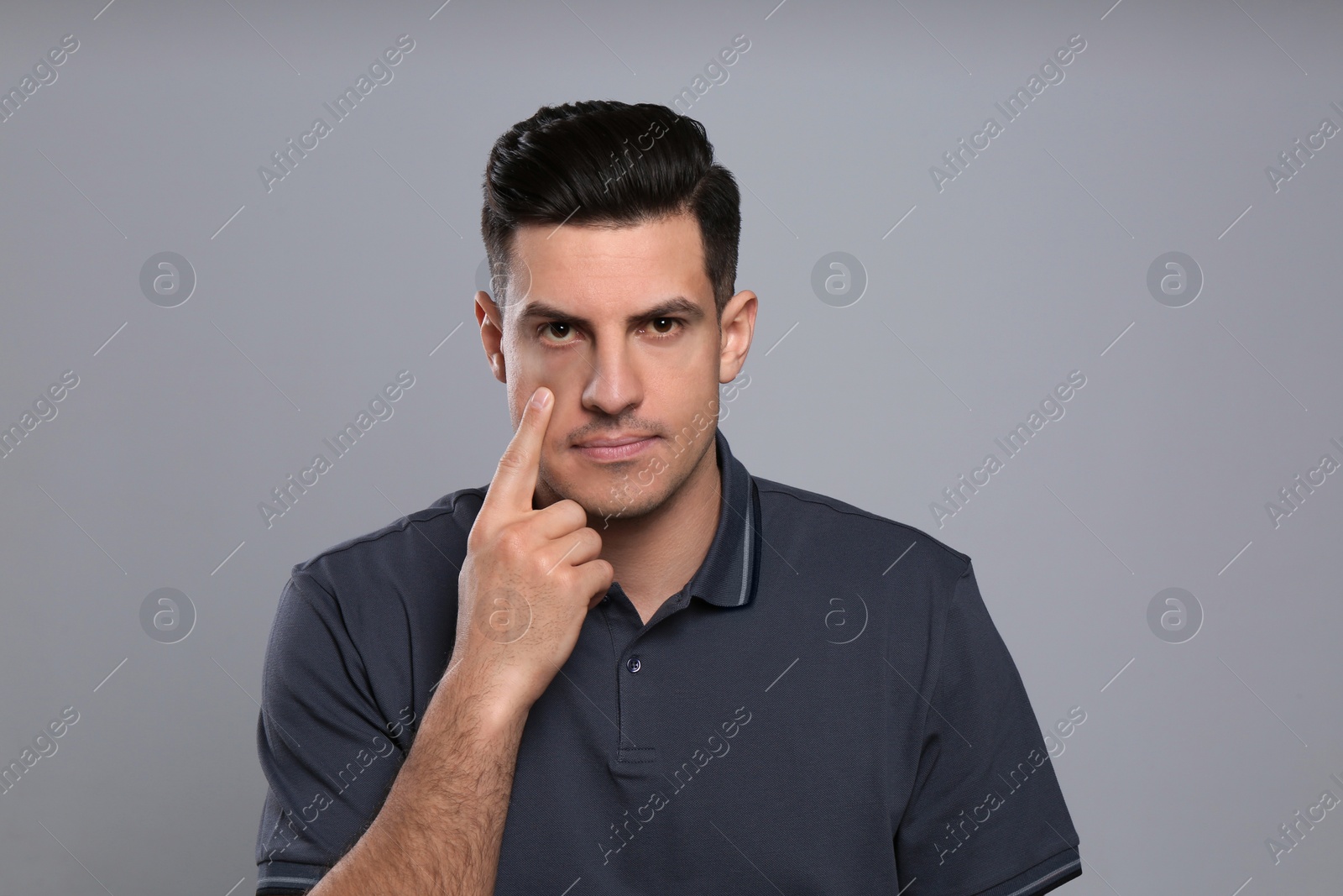 Photo of Man checking his health condition on grey background. Yellow eyes as symptom of problems with liver