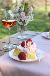 Photo of Glass of wine and cake on table served for romantic date in garden