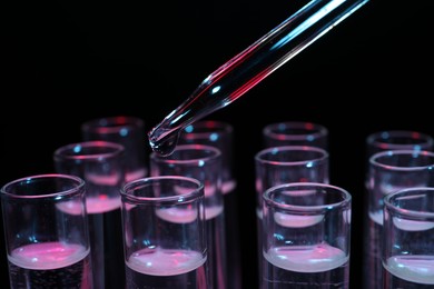 Photo of Dripping reagent into test tube on black background, closeup. Laboratory analysis