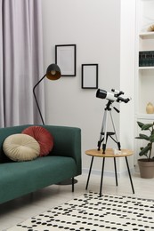 Tripod with modern telescope on table in living room