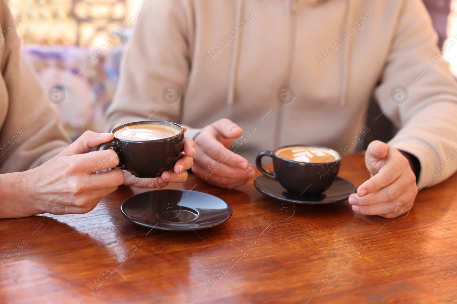 Photo of Couple with cups of aromatic coffee at wooden table, closeup