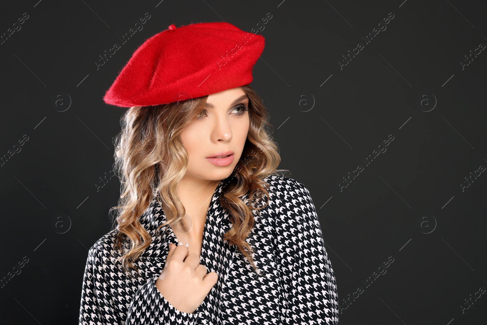 Photo of Young woman with beautiful makeup in red beret against black background