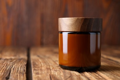 Photo of Jar of luxury cream on wooden table, closeup. Space for text