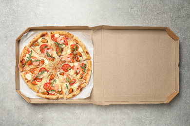 Delicious seafood pizza in box on light grey table, top view