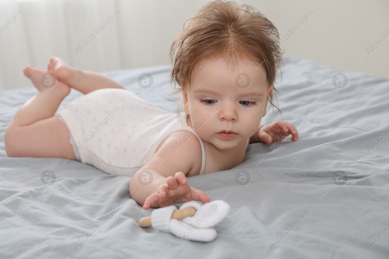 Photo of Cute little baby with toy on bed