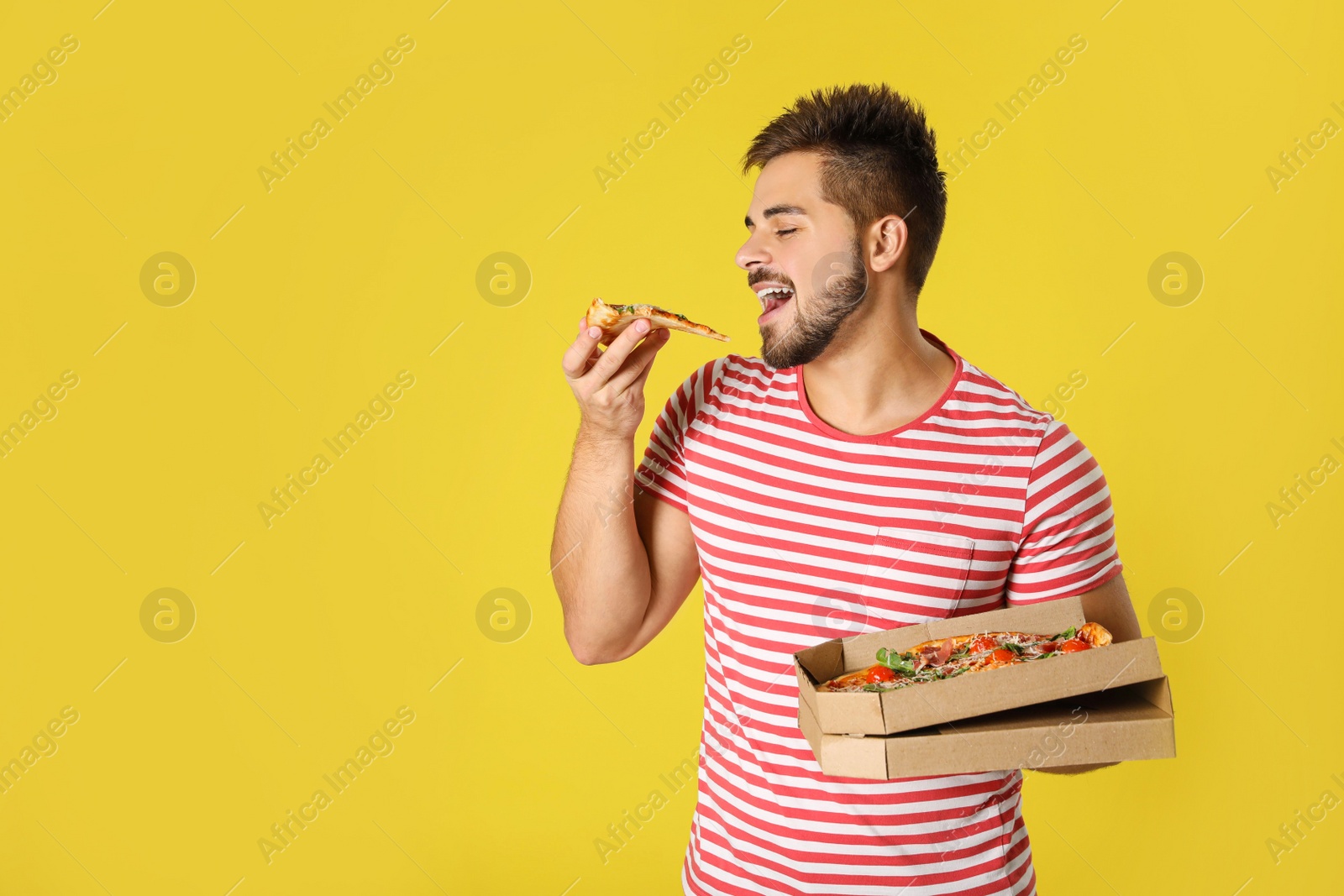 Photo of Handsome man eating tasty pizza on yellow background