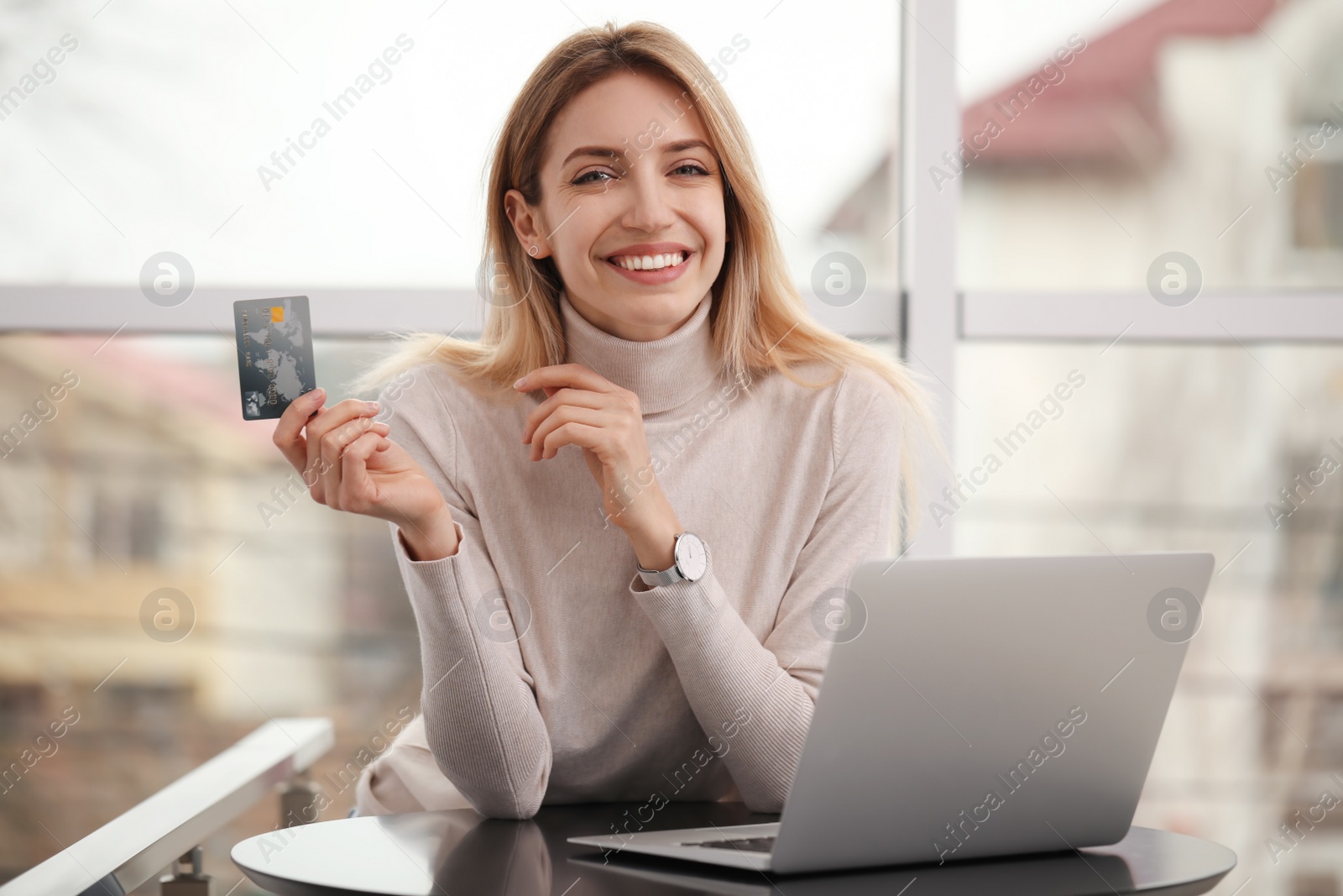 Photo of Woman with credit card using laptop for online shopping indoors
