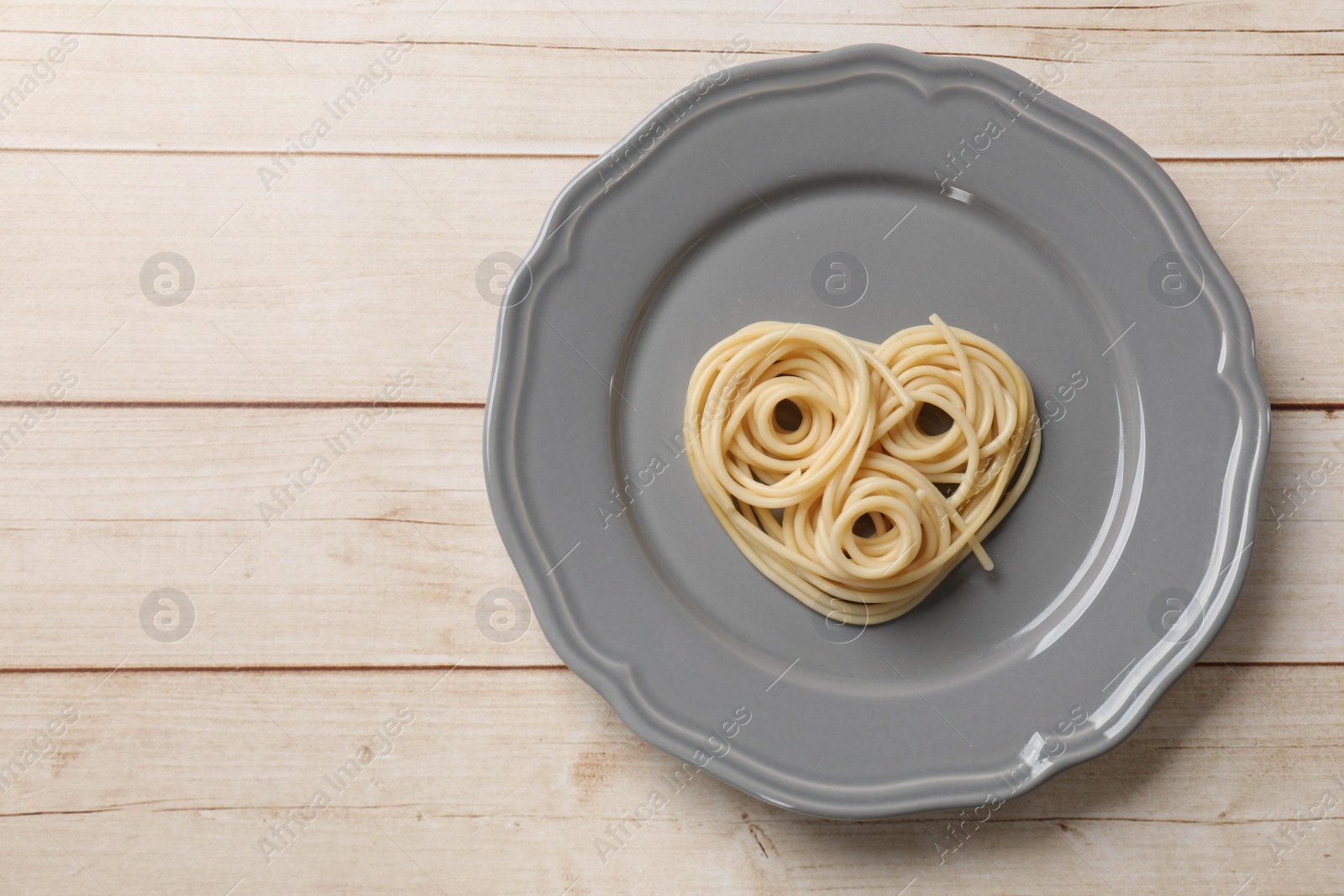 Photo of Heart made of tasty spaghetti on wooden table, top view. Space for text