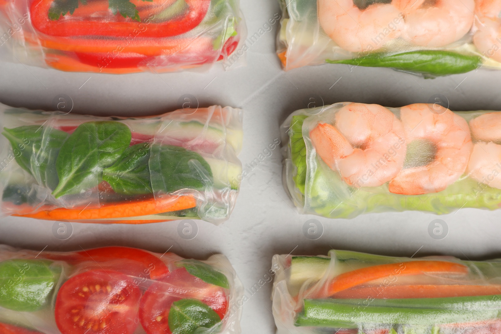 Photo of Spring rolls wrapped in rice paper on light table, flat lay