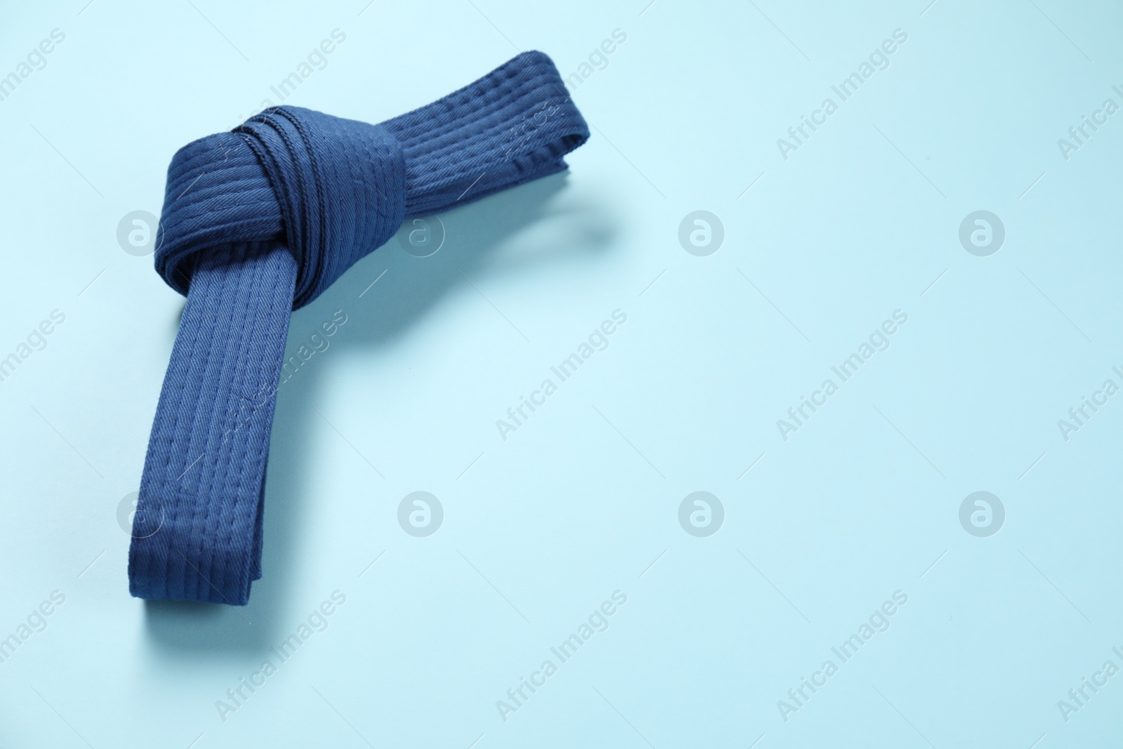 Photo of Karate belt on light blue background, space for text