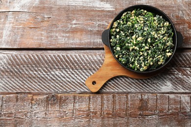 Photo of Tasty spinach dip with eggs in dish on wooden table, top view. Space for text