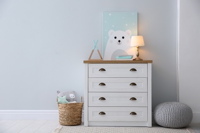 Photo of Modern white chest of drawers near light wall in child room, space for text. Interior design