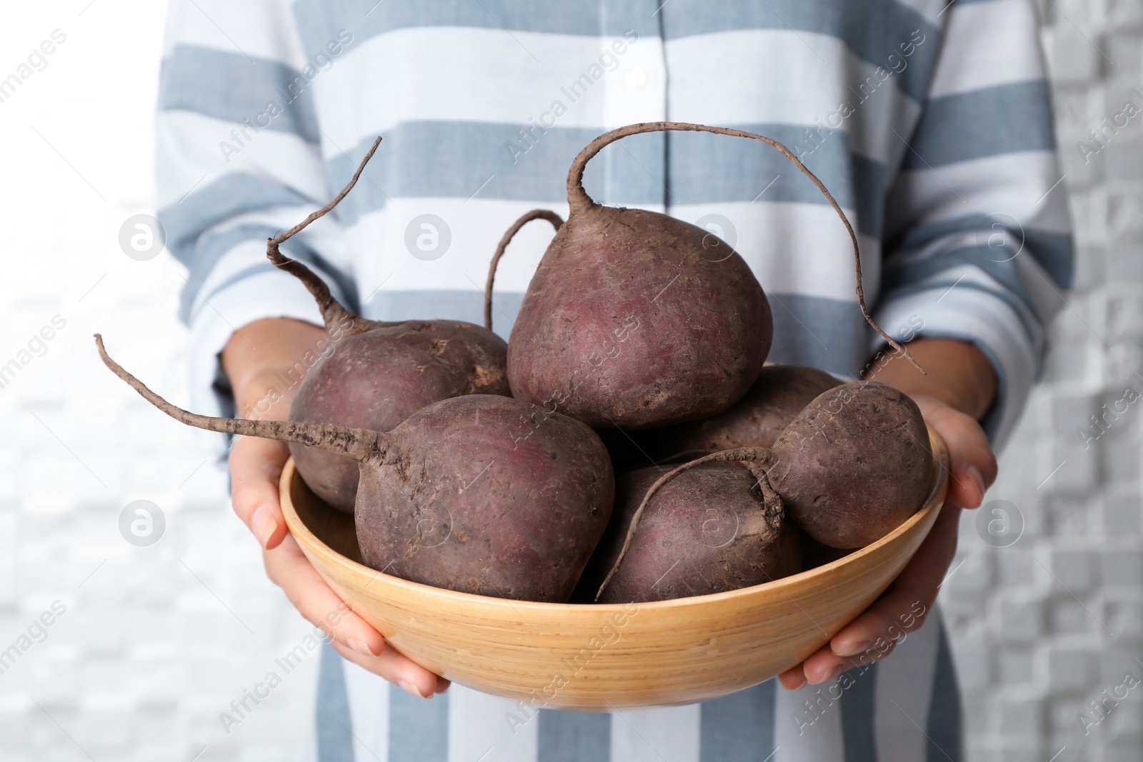 Photo of Woman holding bowl with beets on light background