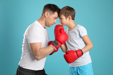 Photo of Dad and his son with boxing gloves on color background