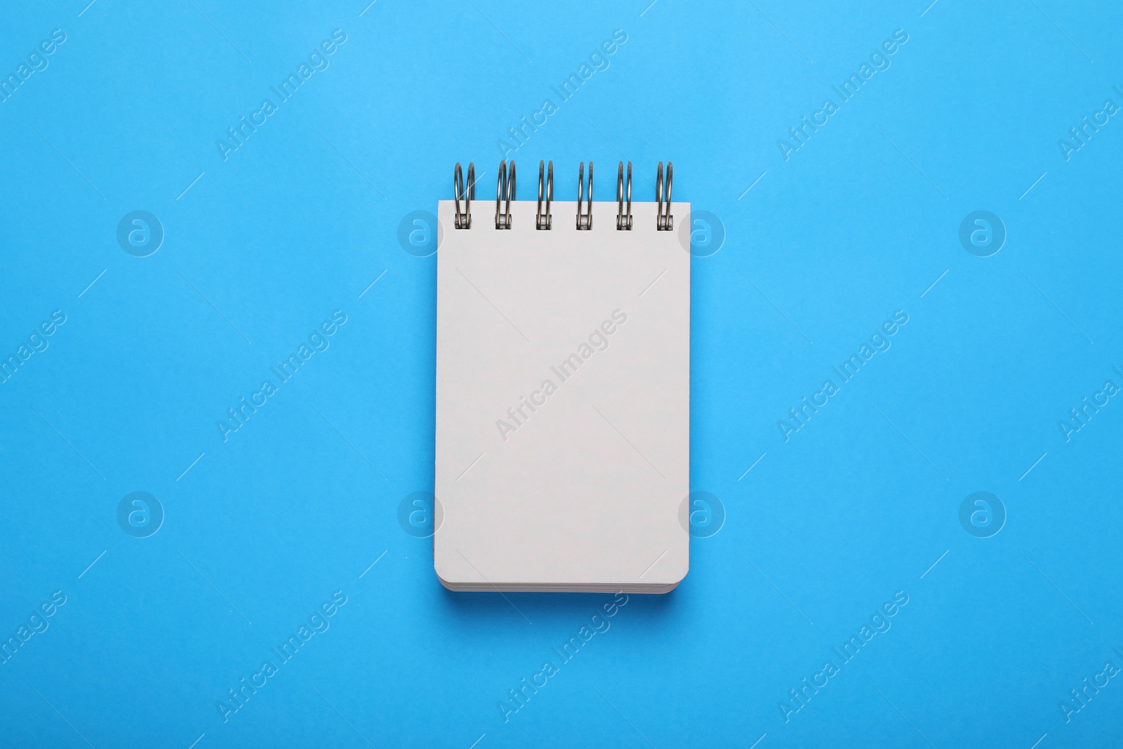 Photo of Open notebook on light blue background, top view